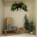 Decorative setup with Christmas trees, presents, and a sled in a white cabinet.
