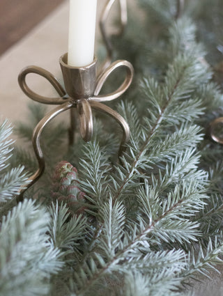 Brass bow candlestick set among the noble pine garland
