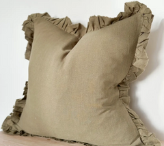Olive linen cushion cover with ruffled edges displayed on a wooden surface