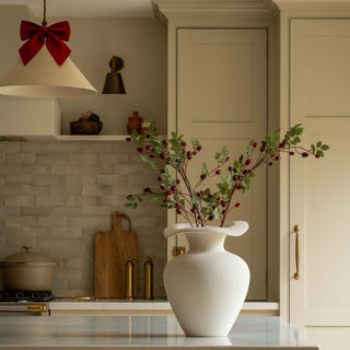 Faux rose hip spray with red berries styled in a cream kitchen for Christmas