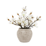Faux white flower arrangement in a textured beige pot on a white background