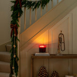 Decorative staircase with Christmas garland, candle, pinecones, and a trumpet.