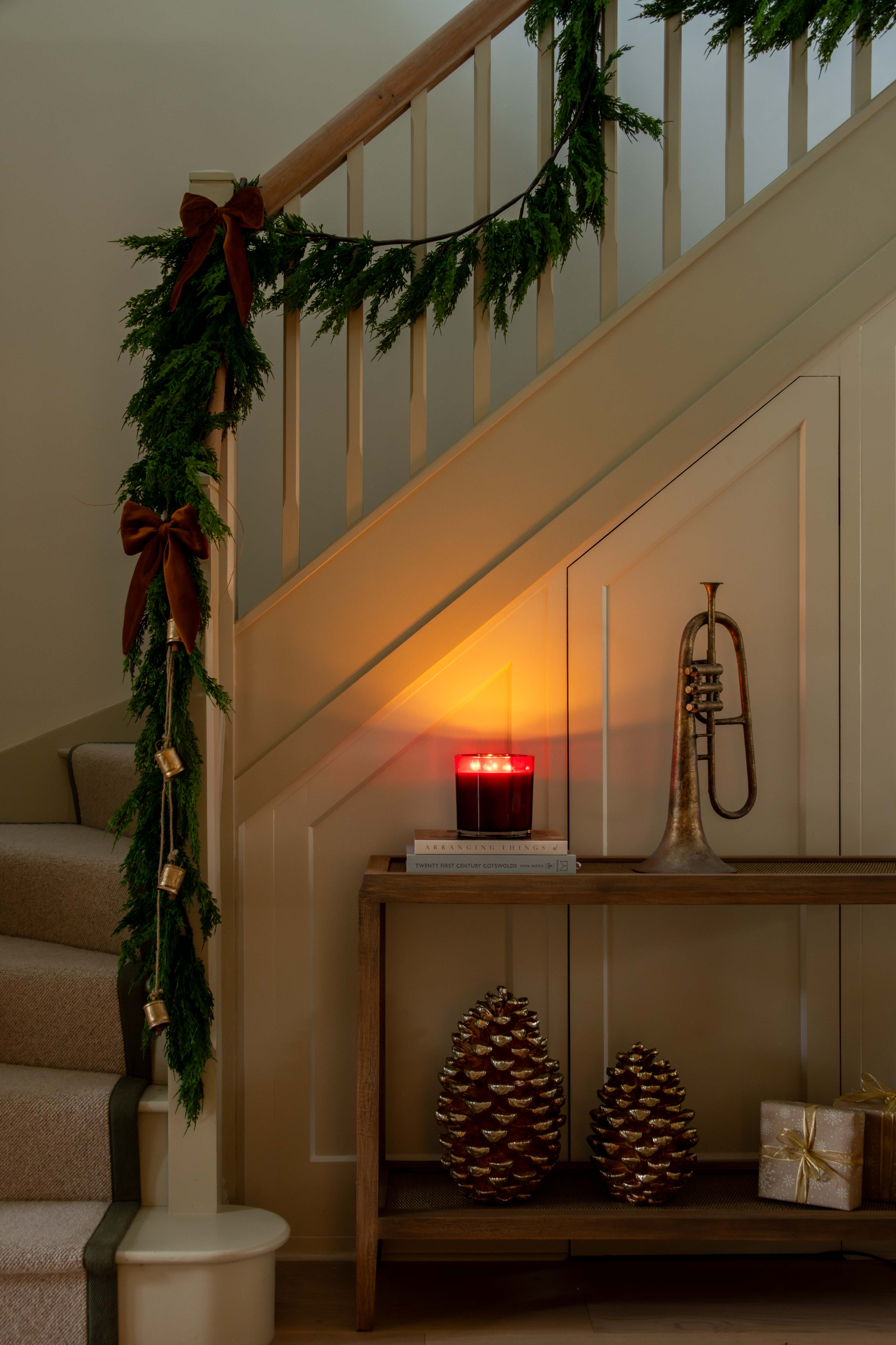 Decorative staircase with Christmas garland, candle, pinecones, and a trumpet.