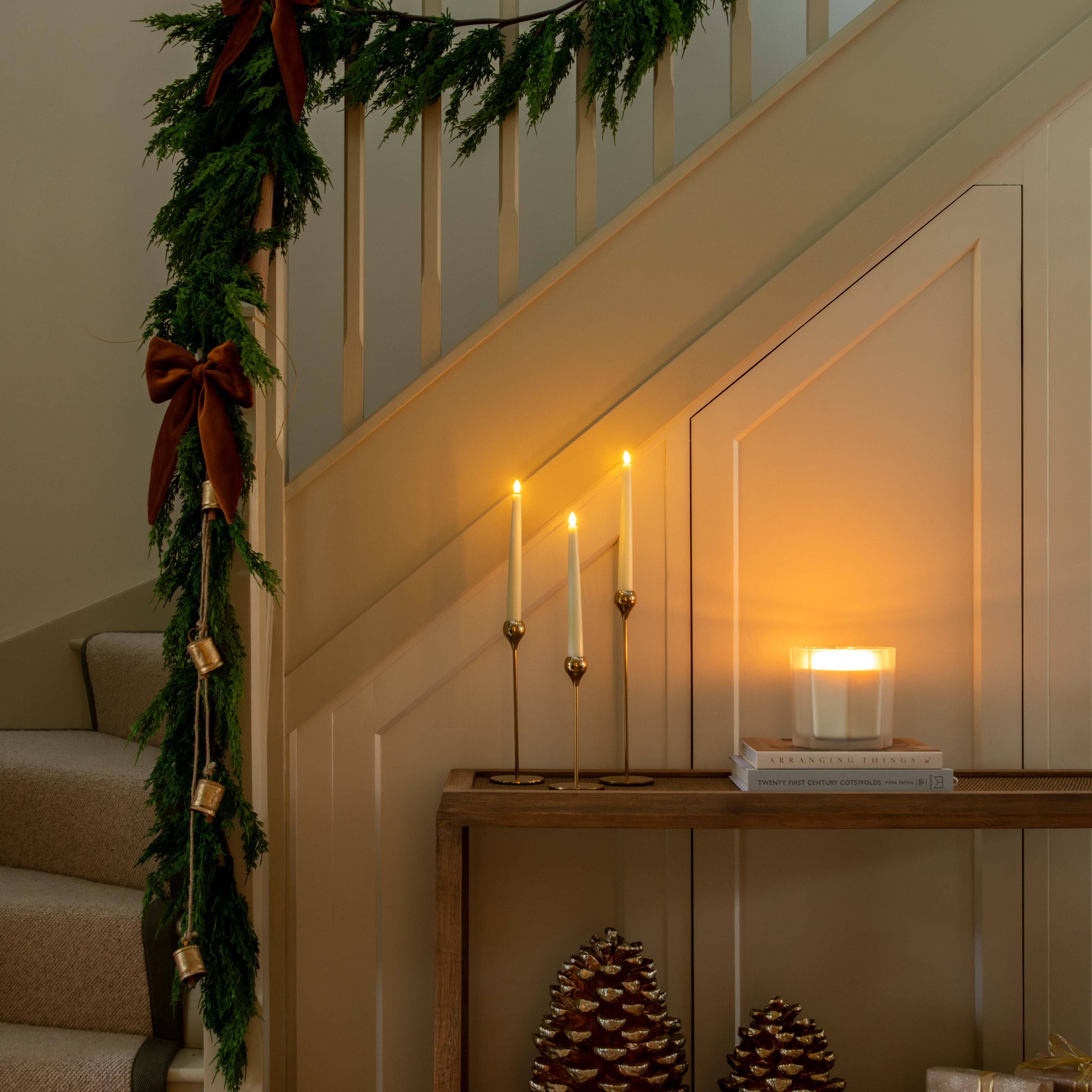 Decorative staircase with greenery, candles, and decorative items in a warm setting.