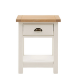 Florence bedside table in oak and white with drawer and open shelf beside a bed