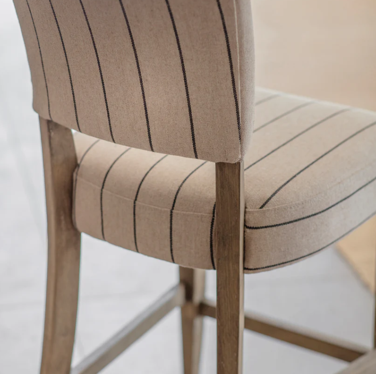 Striped linen counter stool with cushioned seat and wood legs at a modern kitchen island