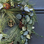 A beautiful full wreath, created using silver dollar eucalyptus, natural eucalyptus, blueberry stems, pine spray and finished with pine cones