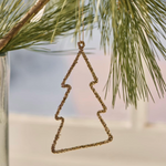 Gold tree-shaped ornament hanging on a branch with a blurred natural background