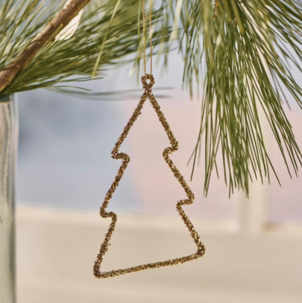 Gold tree-shaped ornament hanging on a branch with a blurred natural background