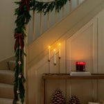 Decorative staircase with garland, candles, and decorative items in a warm setting.
