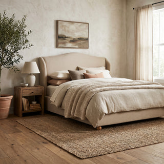 Harlyn winged upholstered bed with camelback linen headboard and wooden bun feet in a calm neutral bedroom