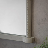 Arched wall mirror with decorative crest and beaded frame in a vintage gray finish