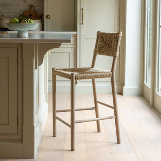 Wooden bar stool in a kitchen setting with light wood flooring and neutral color palette.