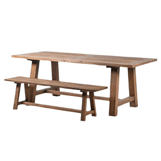 A rustic farmhouse style reclaimed elm dining bench with a matching table in the background.