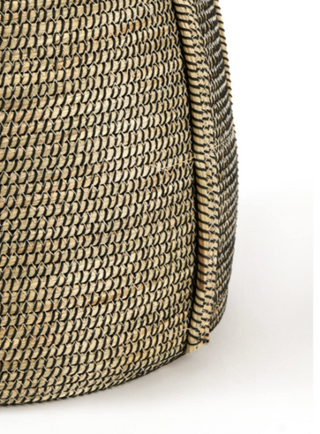 Close-up of a woven straw bag showing the detailed texture and natural beige-brown color of the material against a white background.