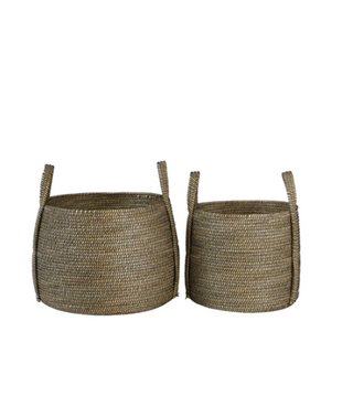 Two round woven storage baskets made from natural seagrass or straw, one larger and one smaller, both featuring integrated side handles, shown against a plain white background.