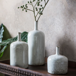 Set of three white ceramic vases with soft white glaze and textured bases styled on wooden console