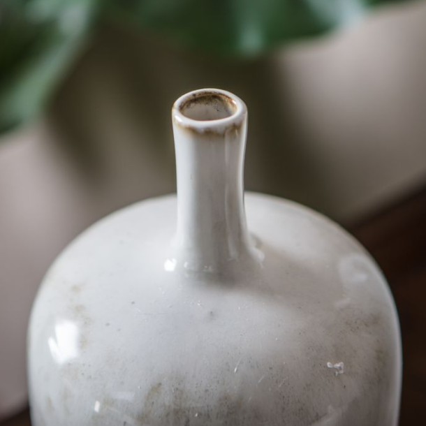 White ceramic bottle with a narrow neck against a blurred background