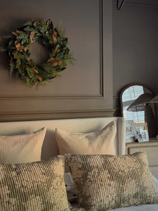 Magnolia wreath on a charcoal front door flanked by potted plants