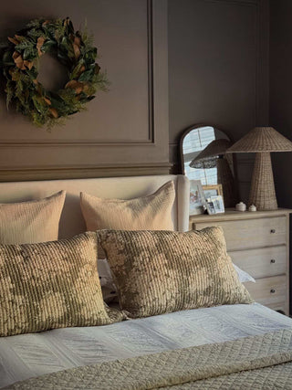 Magnolia wreath above a linen bed with patterned cushions
