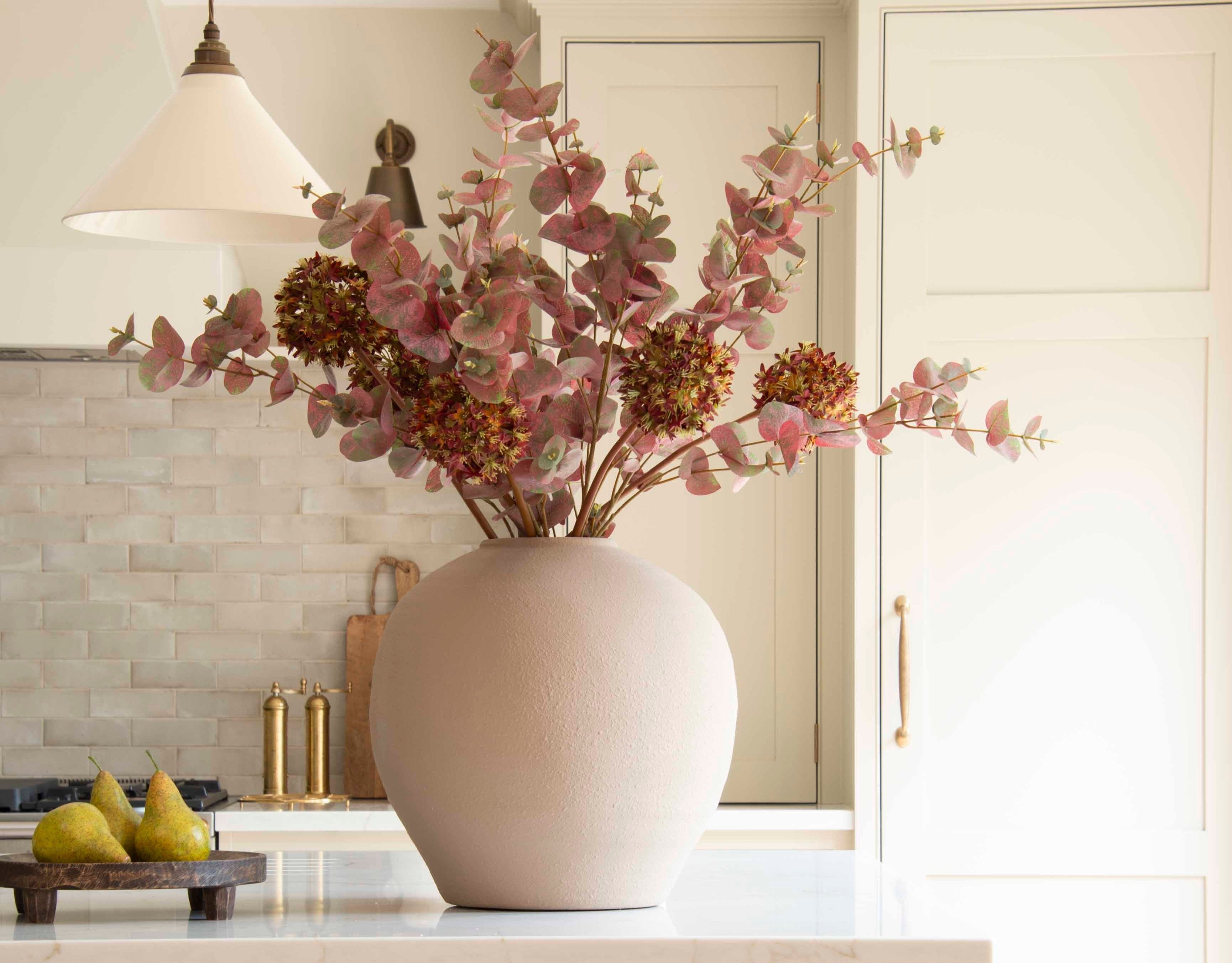 A single stem of lifelike faux eucalyptus in burgundy and green