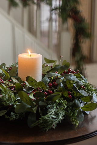 Small 30cm olive leaf and red berry Christmas wreath around a pillar candle