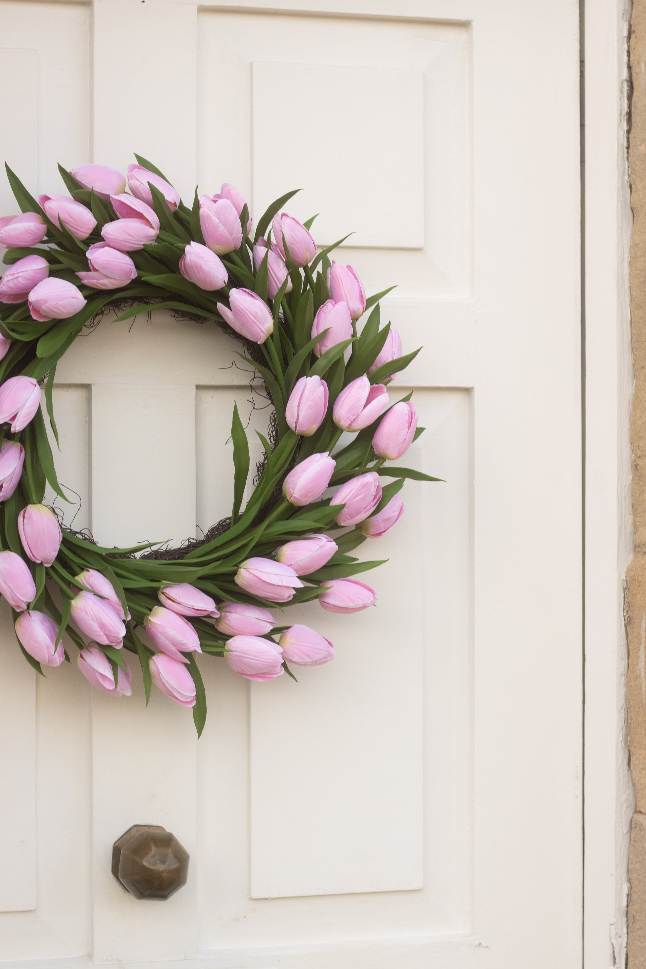 Pink tulip wreath on a white door