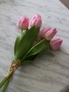 Bouquet of pink tulips tied with twine on a marble surface