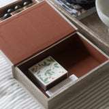 Open wooden box with a decorative item on a striped fabric surface