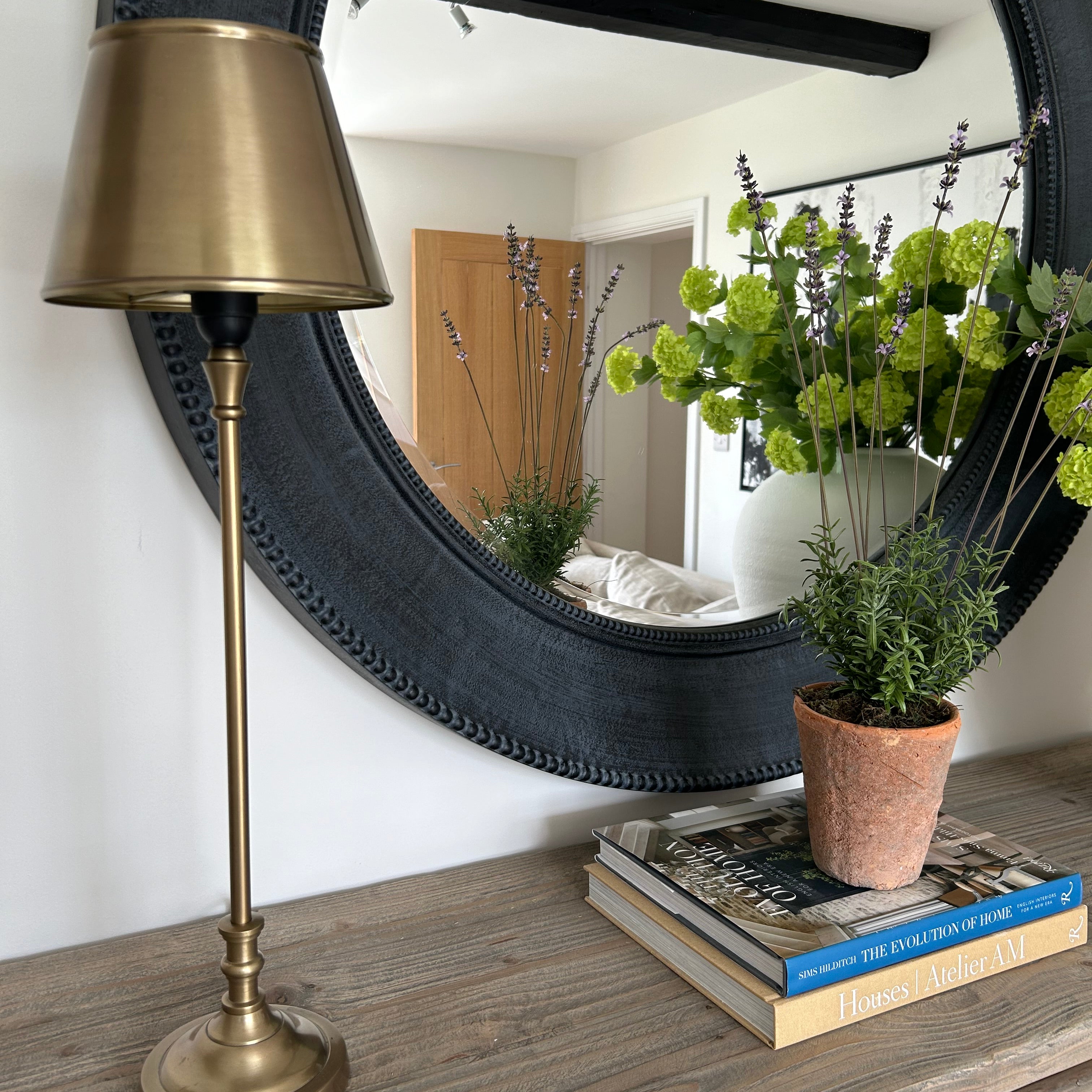 Brass lamp standing on a console table, next to a mirror