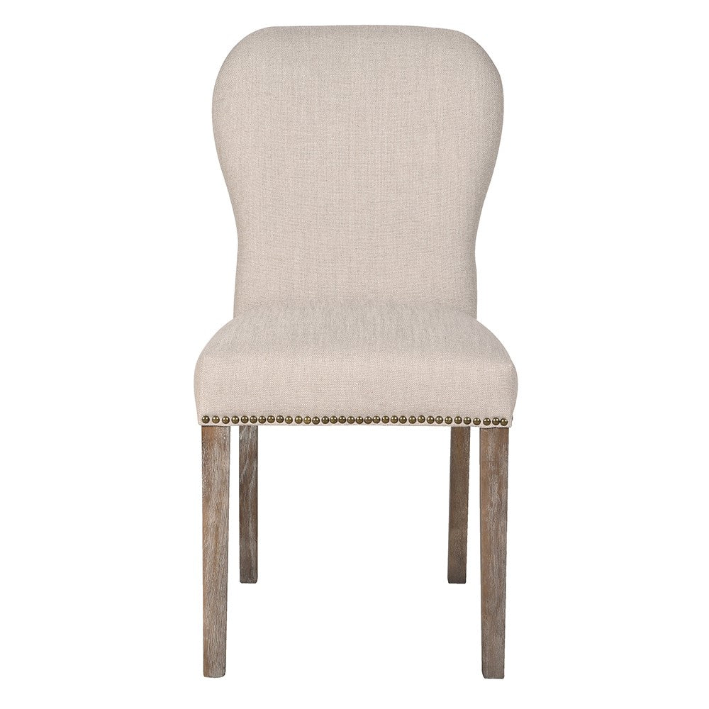 Langdale upholstered dining chair showing curved roll-top back, brass studs and limed oak legs