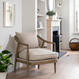 Linen occasional armchair with solid wood frame, curved arms, and cushioned seat in a modern living room