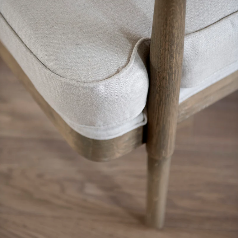 Close-up of a chair with wooden legs and beige cushioned seat on a wooden floor.