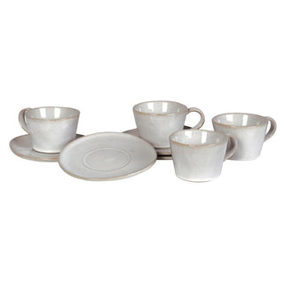 Lulworth set of four stoneware cups and saucers arranged together, showing the low generous cup form, organic-edged saucers and reactive cream-white glaze with russet edge detail