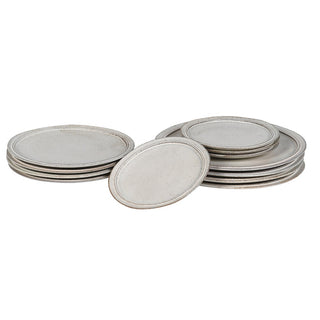 Lulworth 12-piece stoneware dinnerware set arranged in stacked piles, showing three plate sizes in reactive cream-white glaze with russet edge banding