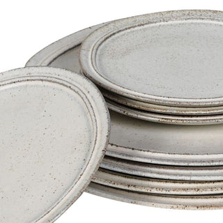 Close-up of stacked Lulworth stoneware plates, showing the russet edge banding, double-ringed rim detail and natural mineral speckle through the glaze