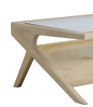 Close-up of a light natural wood coffee table with a clear glass top and angled legs, shown on a white background.