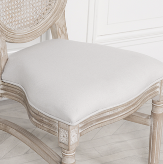 Close-up of the Marlow chair's padded natural linen seat and cane back
