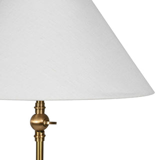 Lamp with white shade and brass base on a white background