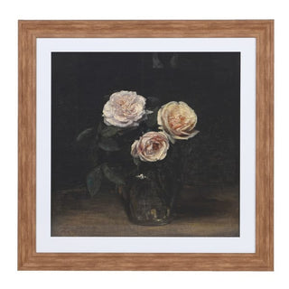A framed still life painting featuring three pale pink and cream roses in a dark vase against a dark background, presented in a light brown wood frame with a white mat board.