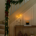 Decorative staircase with Christmas garland, candles, and pinecones.