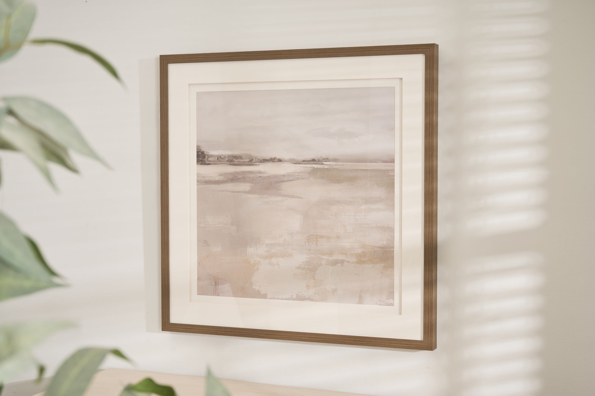Framed abstract landscape print titled "Misty Daybreak" featuring soft gray, beige, and white tones with a minimalist design, displayed in a wood-look frame and white matting.