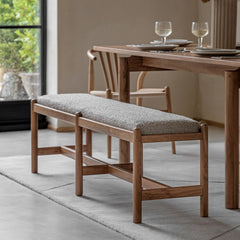Acacia wood bench with grey boucle seat placed in a modern dining room with wooden furniture