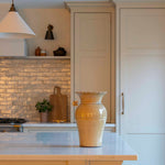 Kitchen with beige cabinets, a vase on the counter, and stools.