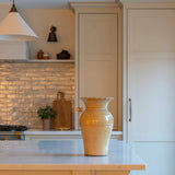 Kitchen with beige cabinets, a vase on the counter, and stools.