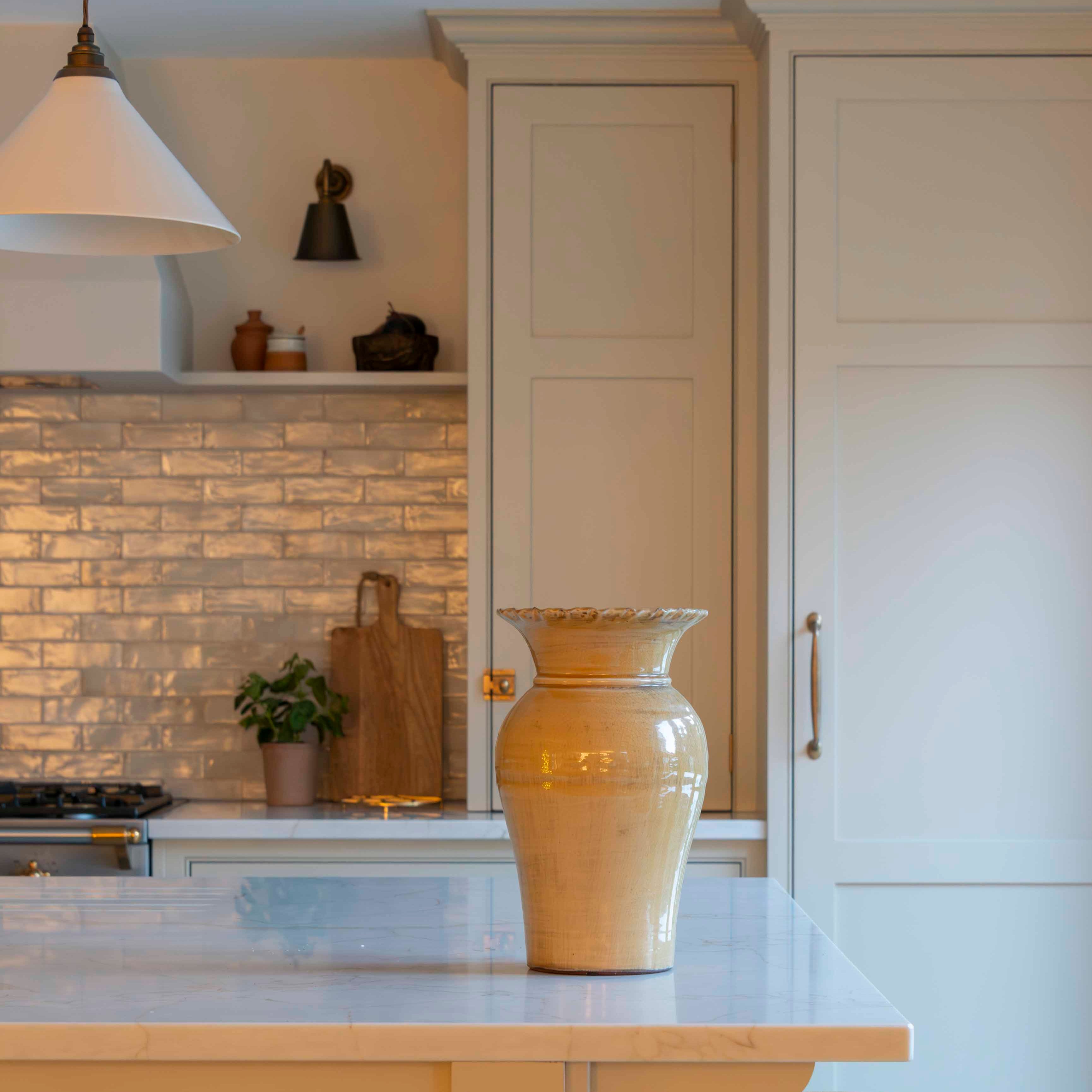 Kitchen with beige cabinets, a vase on the counter, and stools.