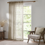 Living room with a large window, beige curtains, and a wooden chair with a cushion.