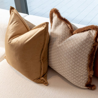 Lechlade beige geometric and amber velvet cushions layered on a sofa