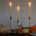 Table setting with candles, pumpkins, and a glass on a wooden surface.