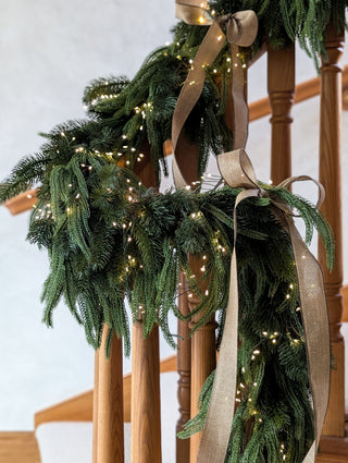 Fir, cypress and pine Christmas garland wound along a wooden banister
